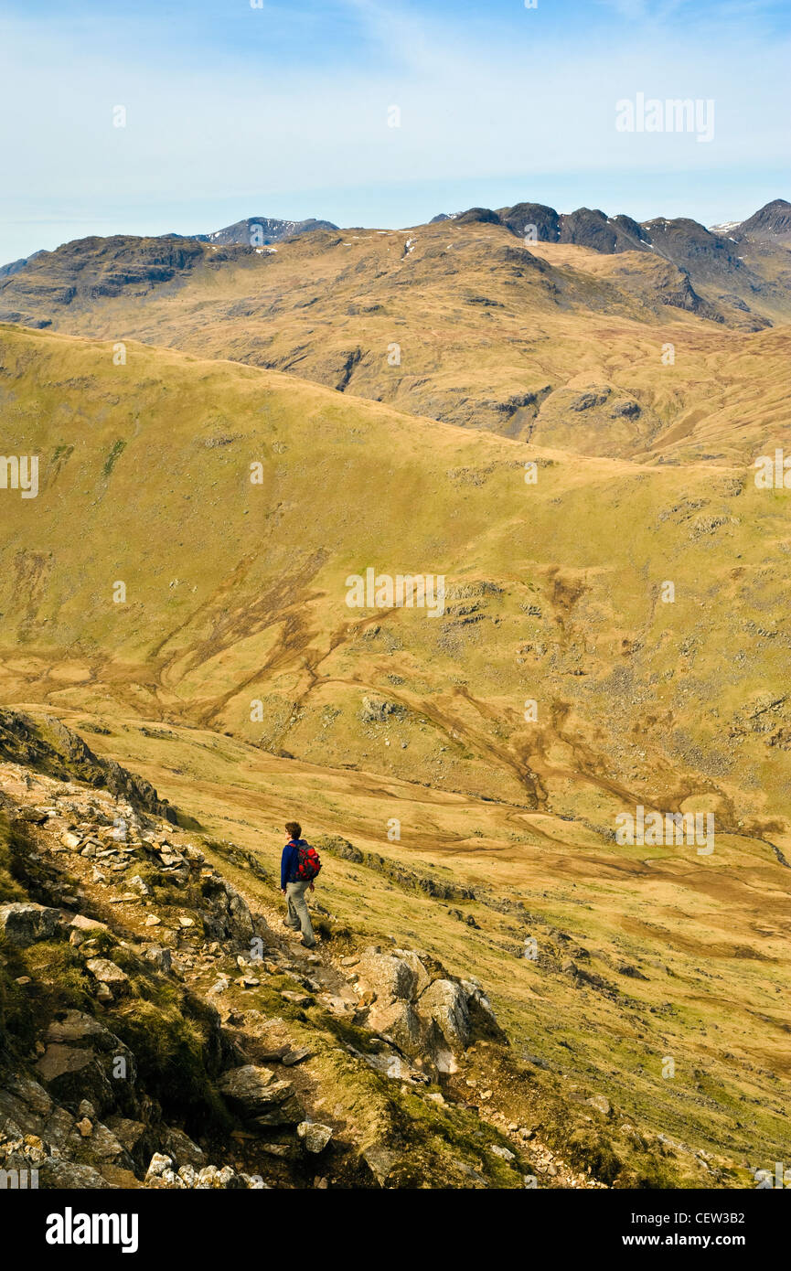 Walker Wetherlam ascendente nel distretto del lago con balze ondulata sullo skyline Foto Stock