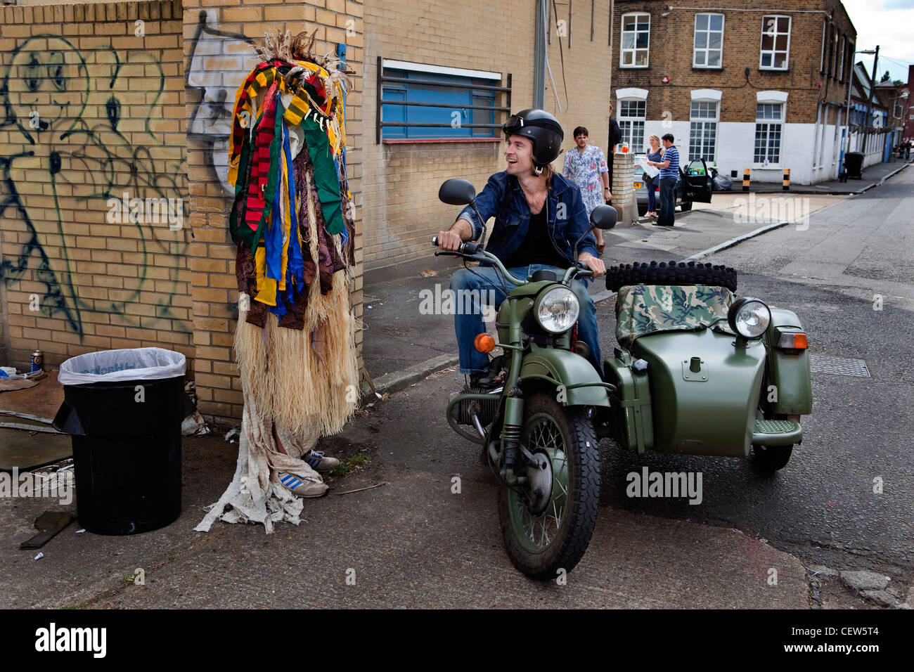 Uomo che indossa tribali costume headless in Hackney Wick Festival parlando di un uomo su una moto con sidecar. Foto Stock