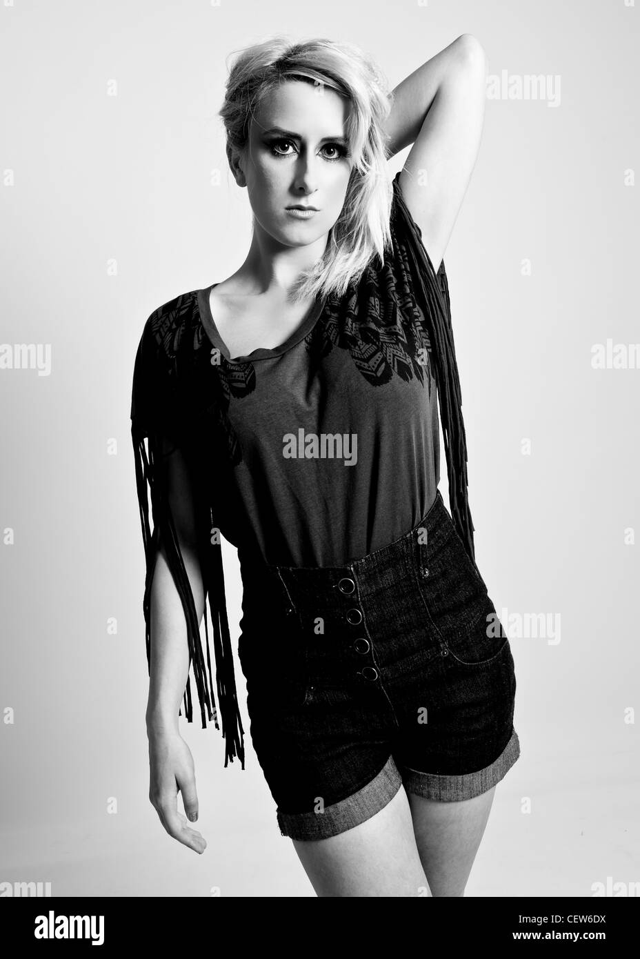 Tre quarti di lunghezza vista frontale in bianco e nero ritratto in studio di slim femmina con mano sinistra dietro la testa Foto Stock