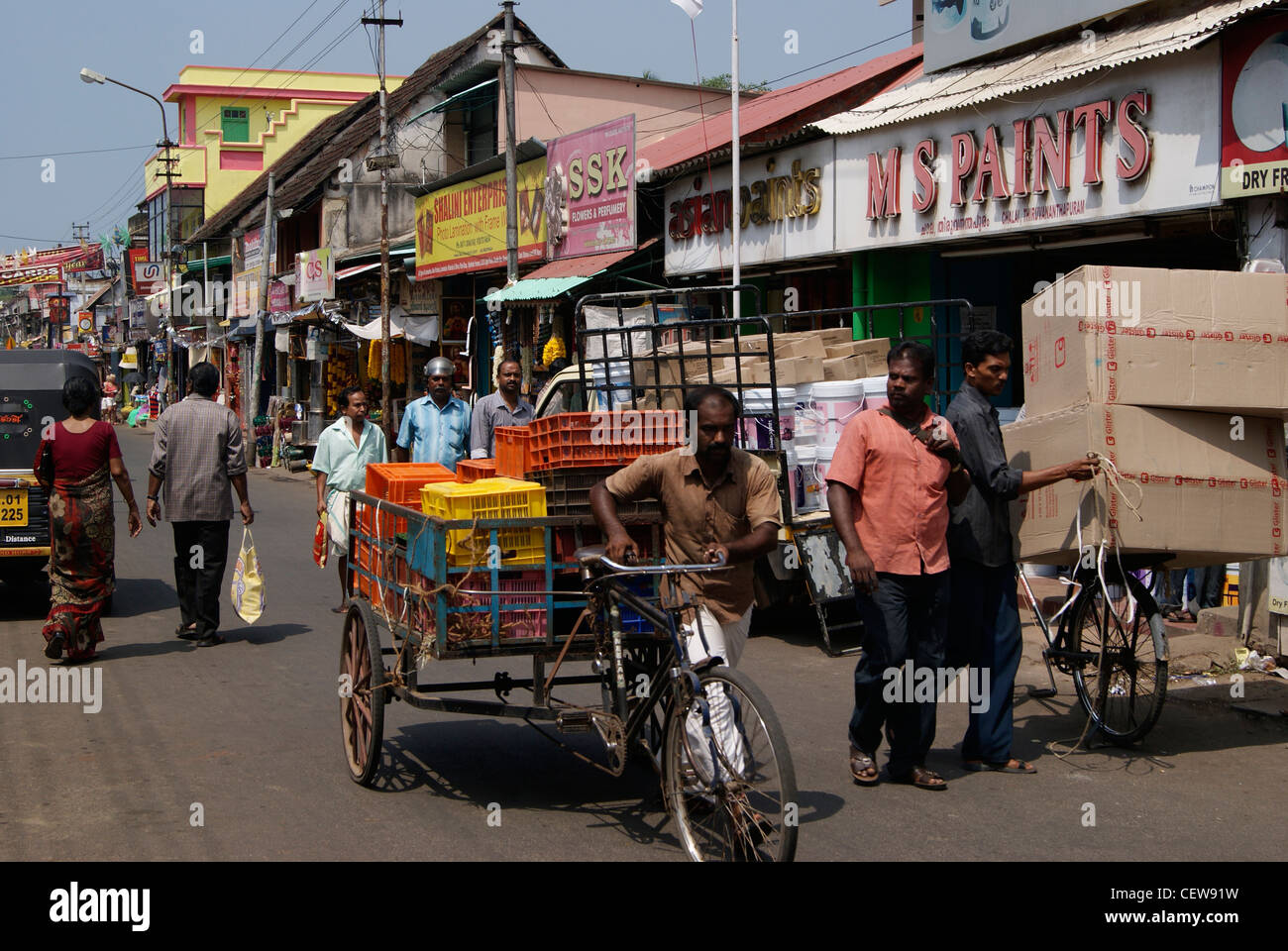 Carico di risciò ciclo tirando l'uomo attraverso il mercato rushy strade del Kerala, India.scene di mercato del Bazaar Chalai India Foto Stock