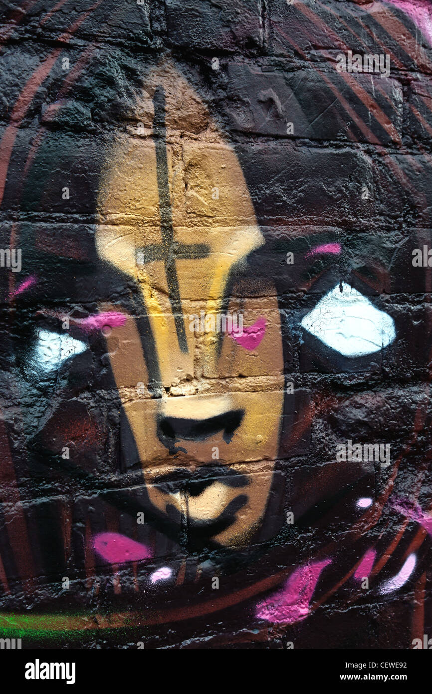Faccia male graffiti immagine con croce sulla sua fronte verniciato a spruzzo su mattoni Foto Stock