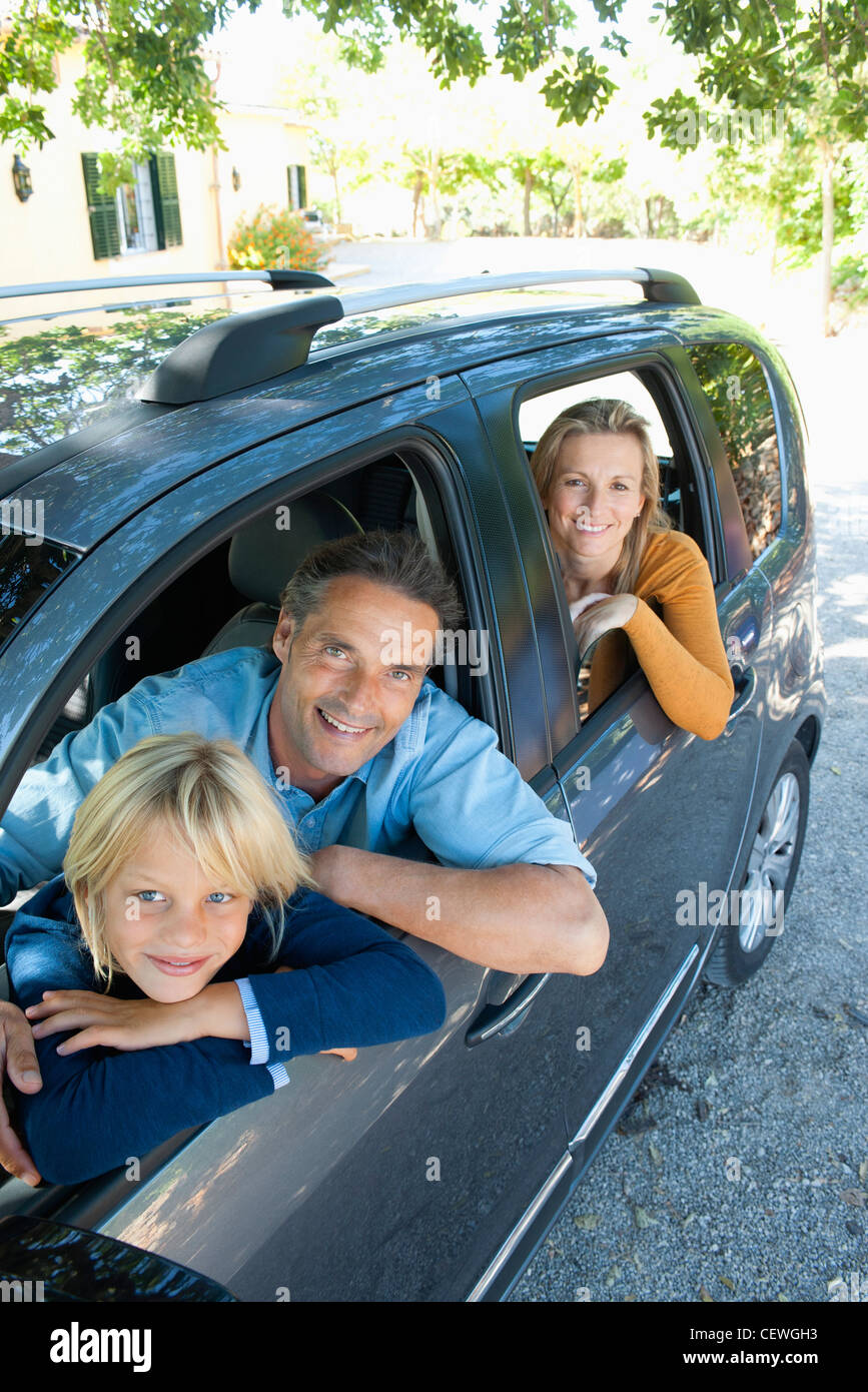Famiglia insieme in auto, sporgersi windows e sorridente in telecamera Foto Stock