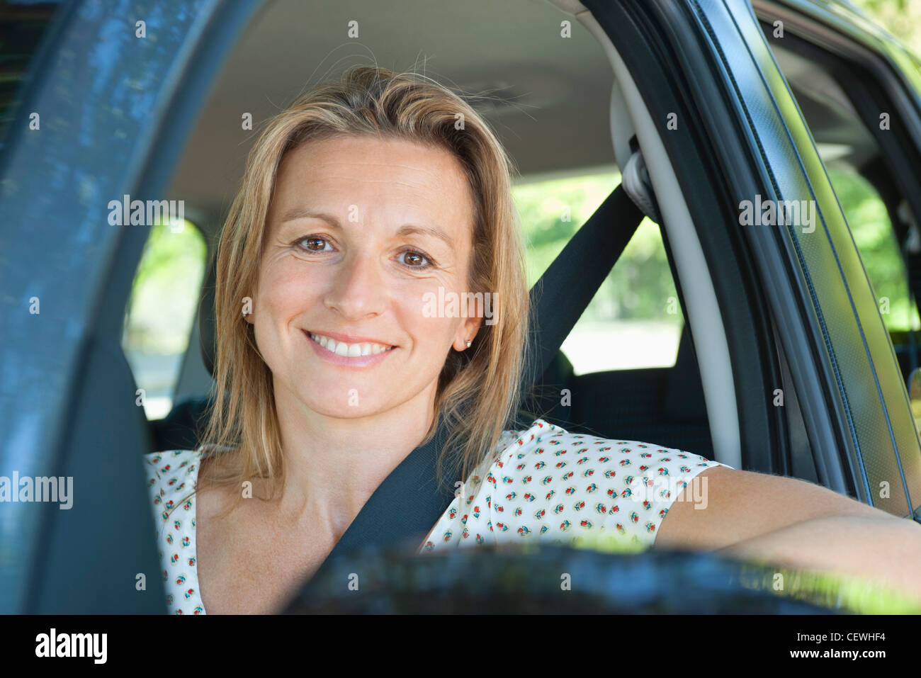 La donna in auto, sorridente fuori finestra, ritratto Foto Stock