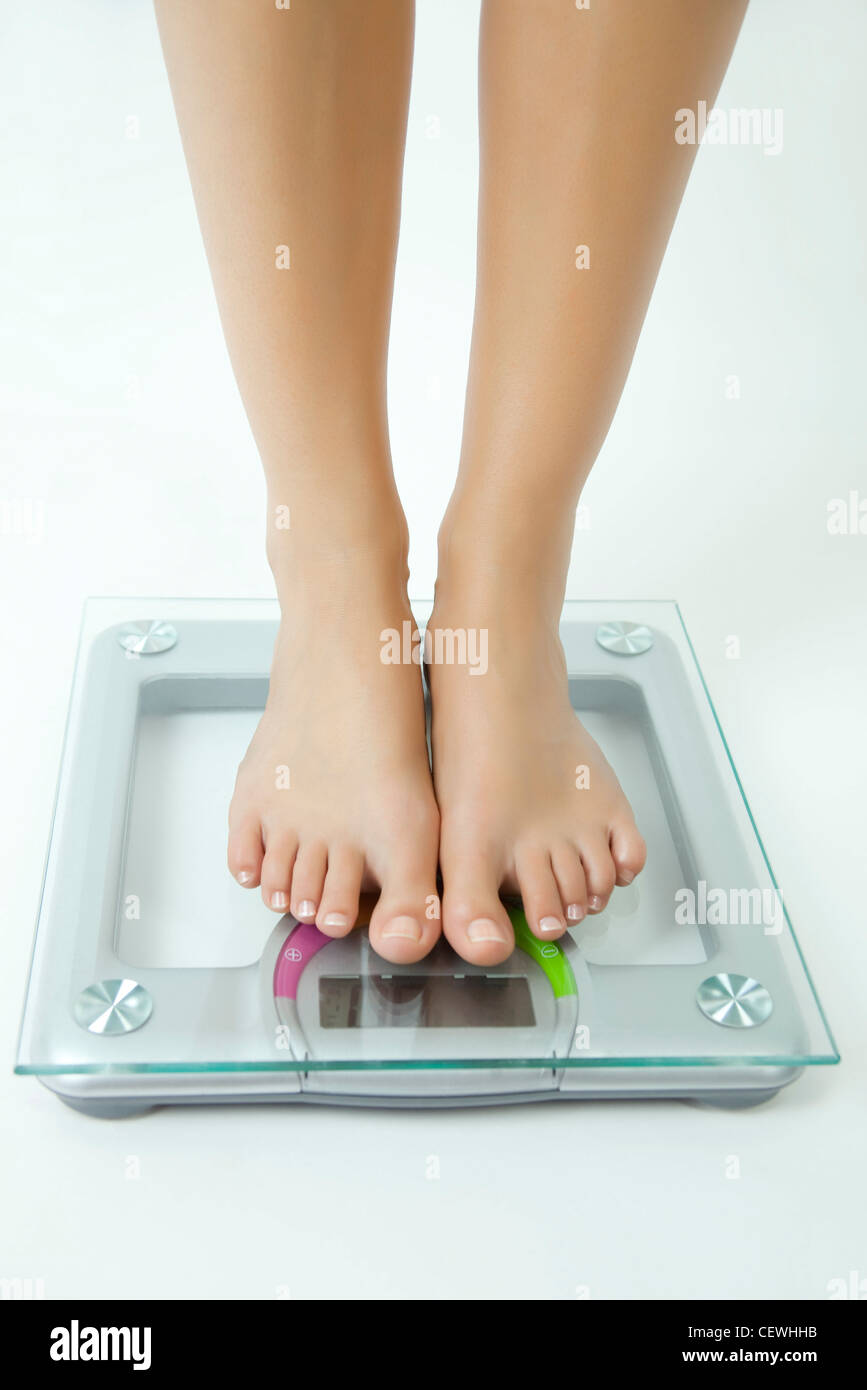 Donna di peso se stessa su una bilancia da bagno, sezione bassa Foto Stock