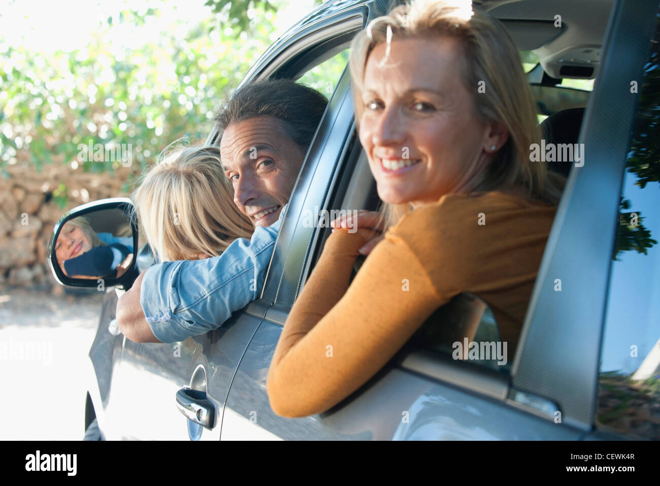 Famiglia insieme in auto, sporgersi windows e sorridente sulle spalle in telecamera Foto Stock