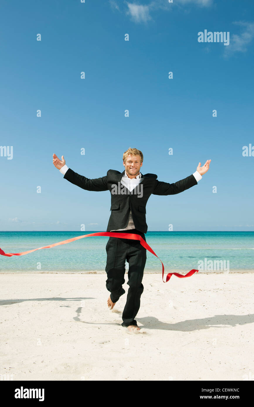 Giovane imprenditore in esecuzione sulla spiaggia verso la linea di finitura Foto Stock