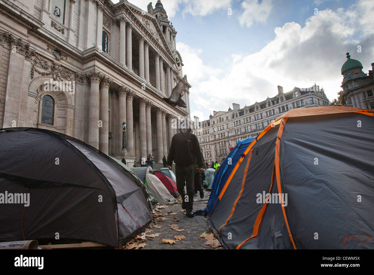 Manifestante mascherato passeggiate tra le tende di occupare Londra OSLX protesta a San Paolo. Foto Stock