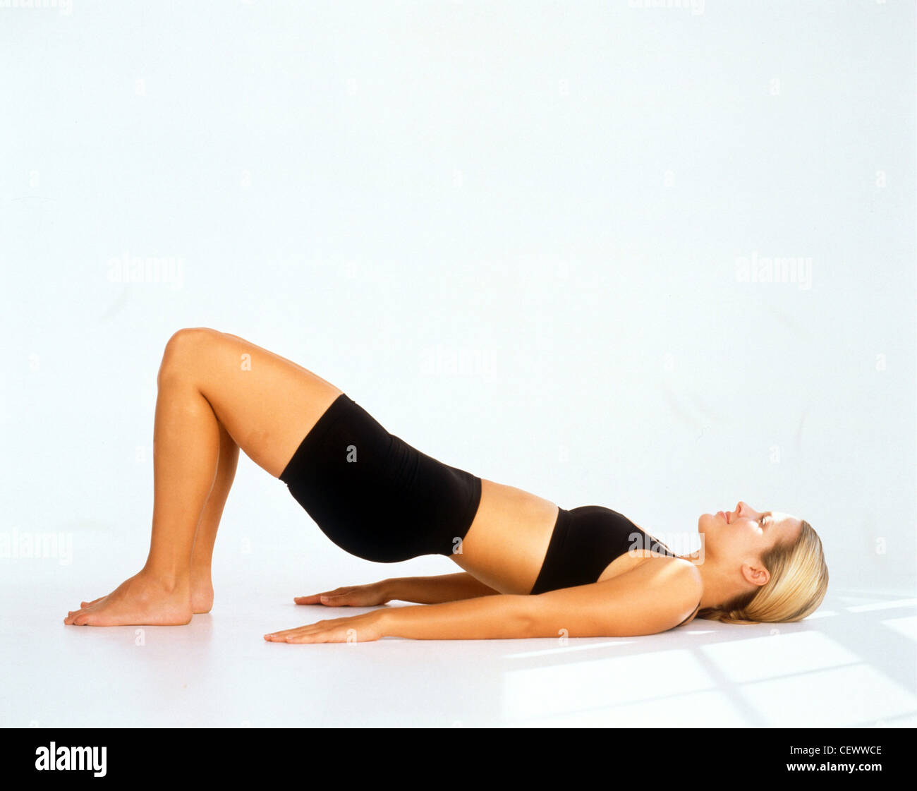 Profilo di donna capelli biondi vestita di nero reggiseno e shorts giacente spalle sulle braccia floand dal lato piedi piatti su flowith Foto Stock