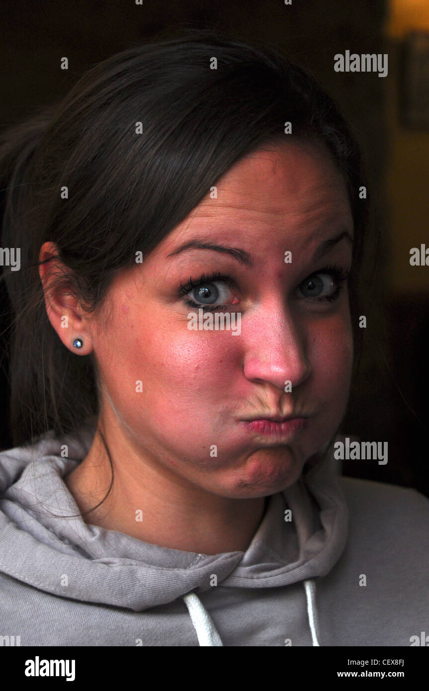 Una ragazza tirando una buffa faccia soffiando fuori la sua guance Foto Stock