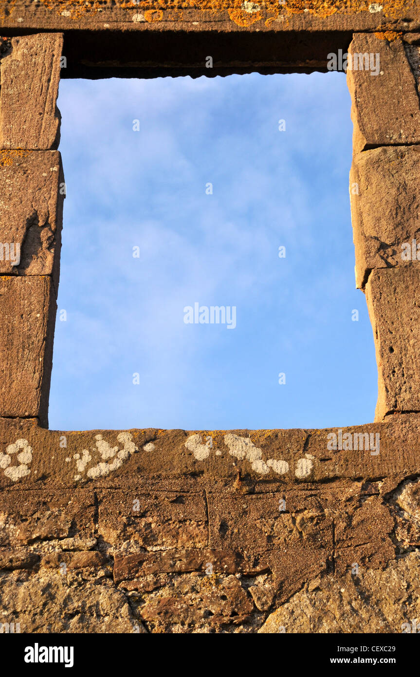 Un vuoto sul telaio di una finestra di un vecchio abbandonato edificio di pietra rivelando blue sky al di là. Foto Stock