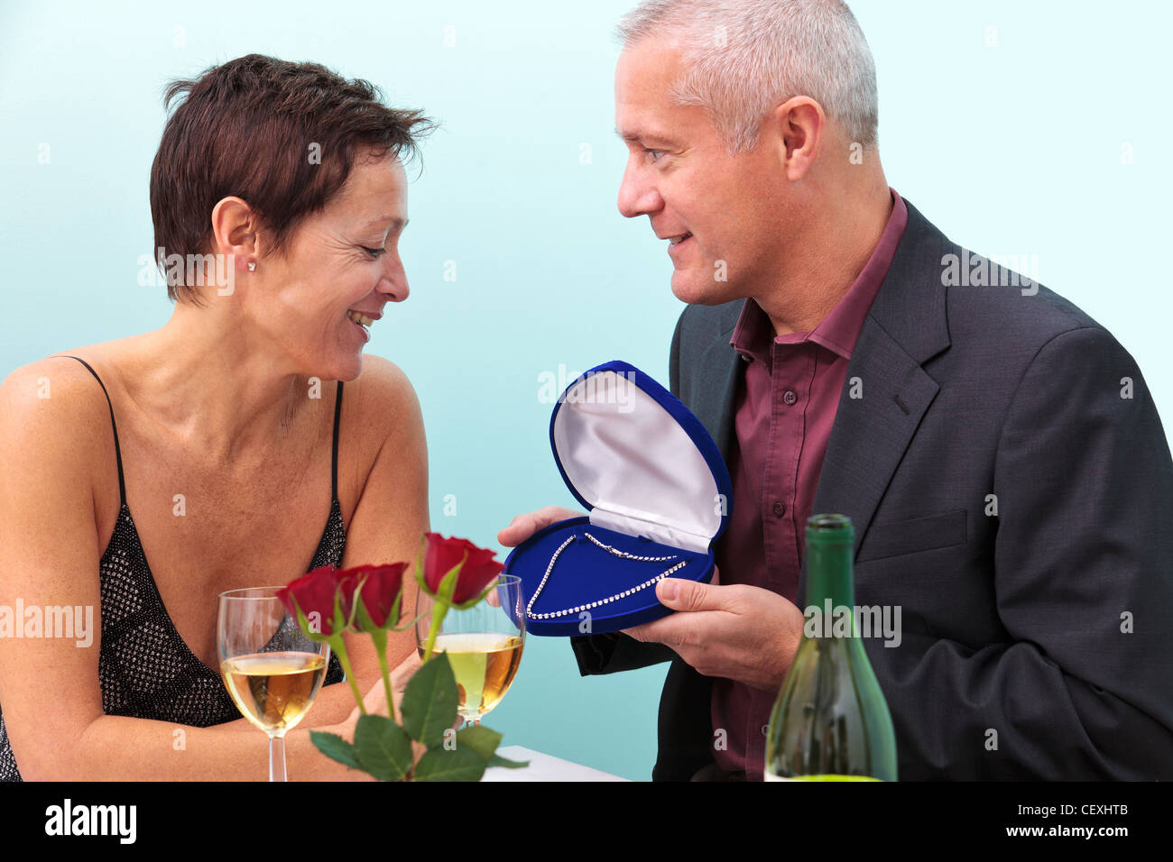 Foto di un uomo maturo dando la sua moglie una collana di diamanti mentre seduti a un tavolo in un ristorante. Foto Stock