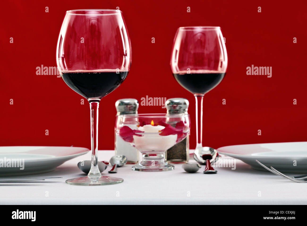 Foto di una messa in tavola con vino rosso bicchieri e una candela flottante Foto Stock