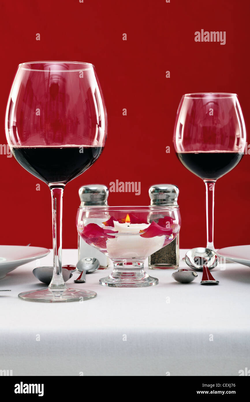 Foto di una messa in tavola con vino rosso bicchieri e una candela galleggiante, copia spazio per aggiungere il proprio messaggio. Foto Stock