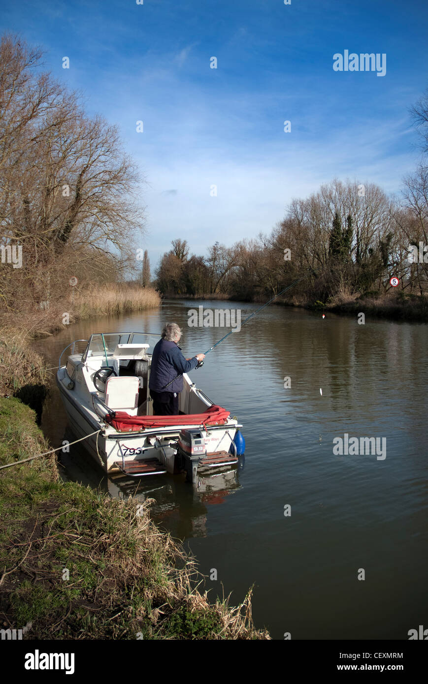 Uomo anziano pesca dalla piccola barca sul fiume waveney a geldeston NORFOLK REGNO UNITO Foto Stock