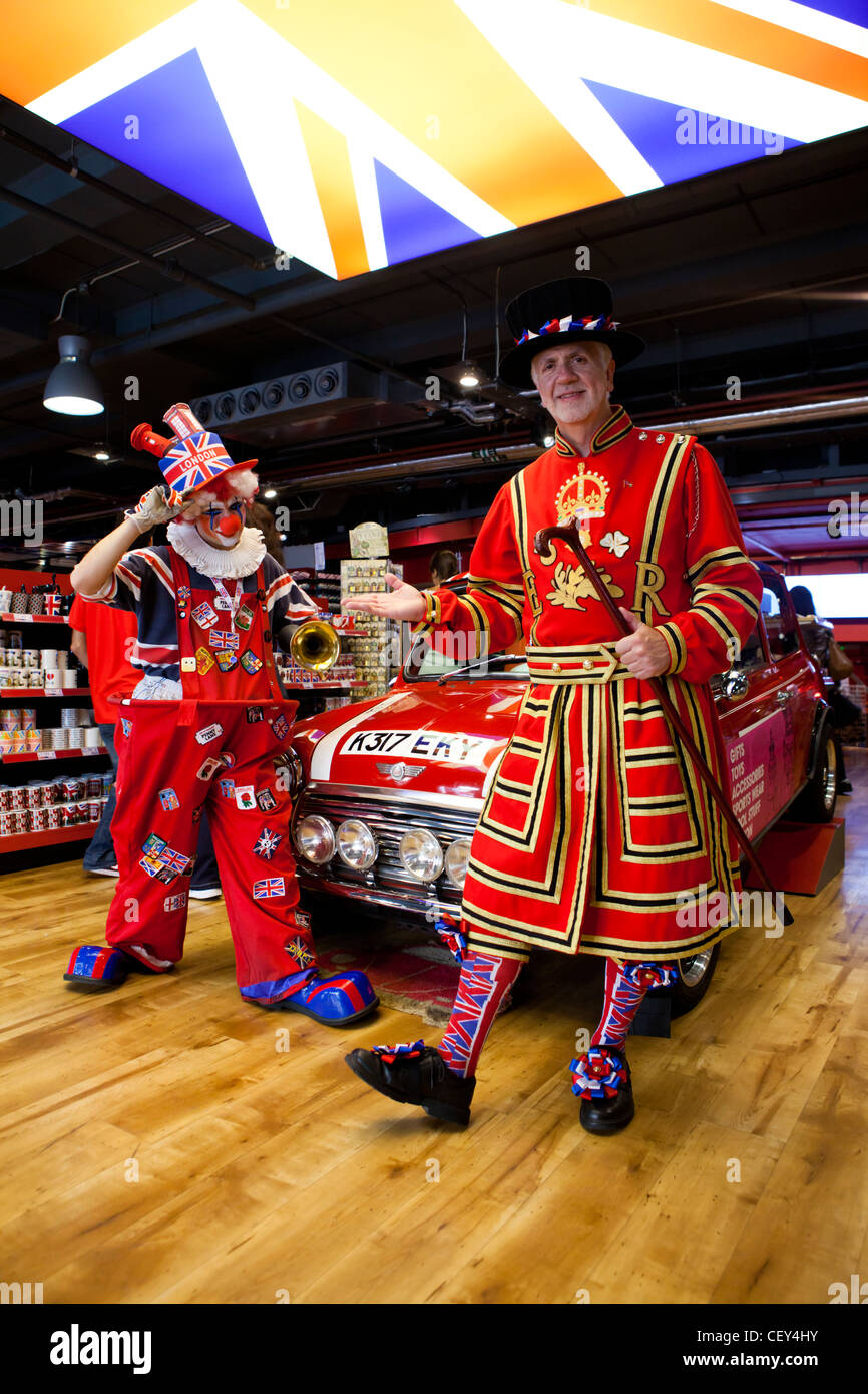 Due cittadini britannici in costume a tema posano con un vecchio Mini Cooper al di sotto di una delle Isole Britanniche bandiera Foto Stock