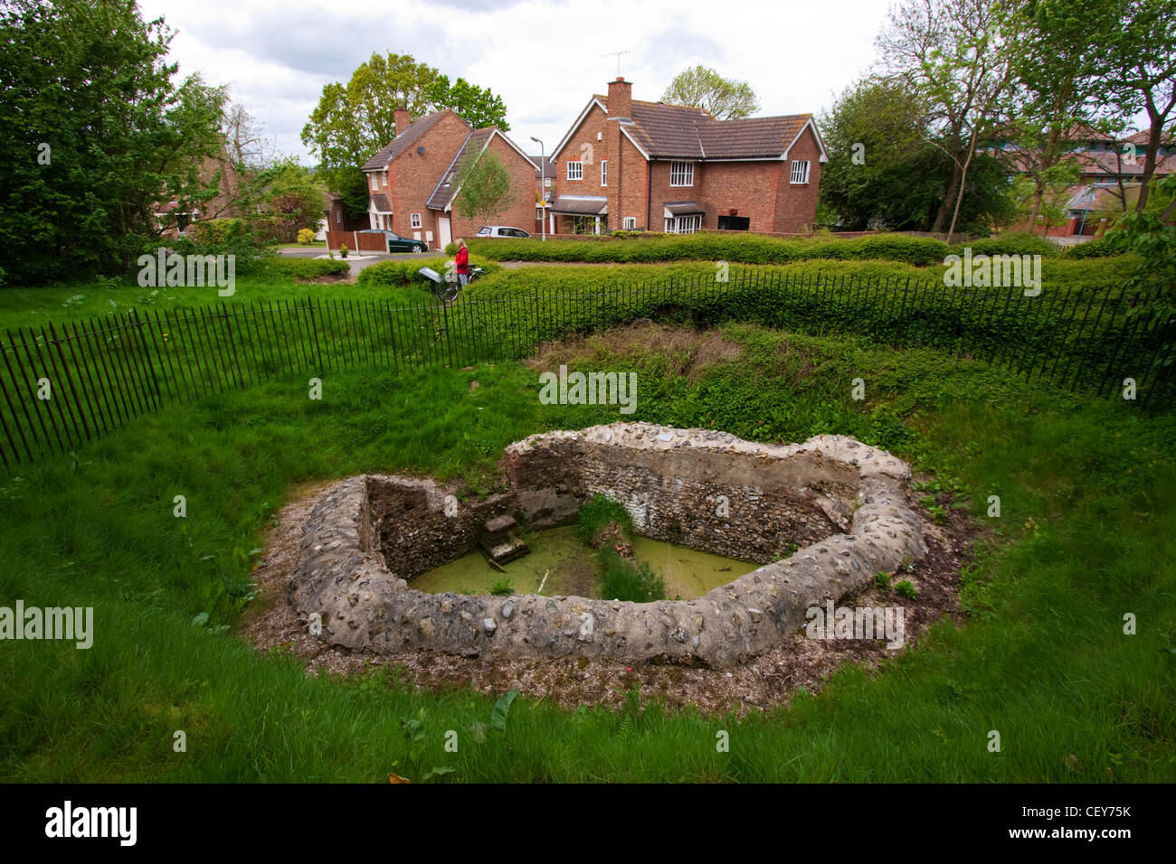 Un ciclista guarda verso i resti di epoca romana di un mulino ad acqua a Canterbury nel Kent Foto Stock