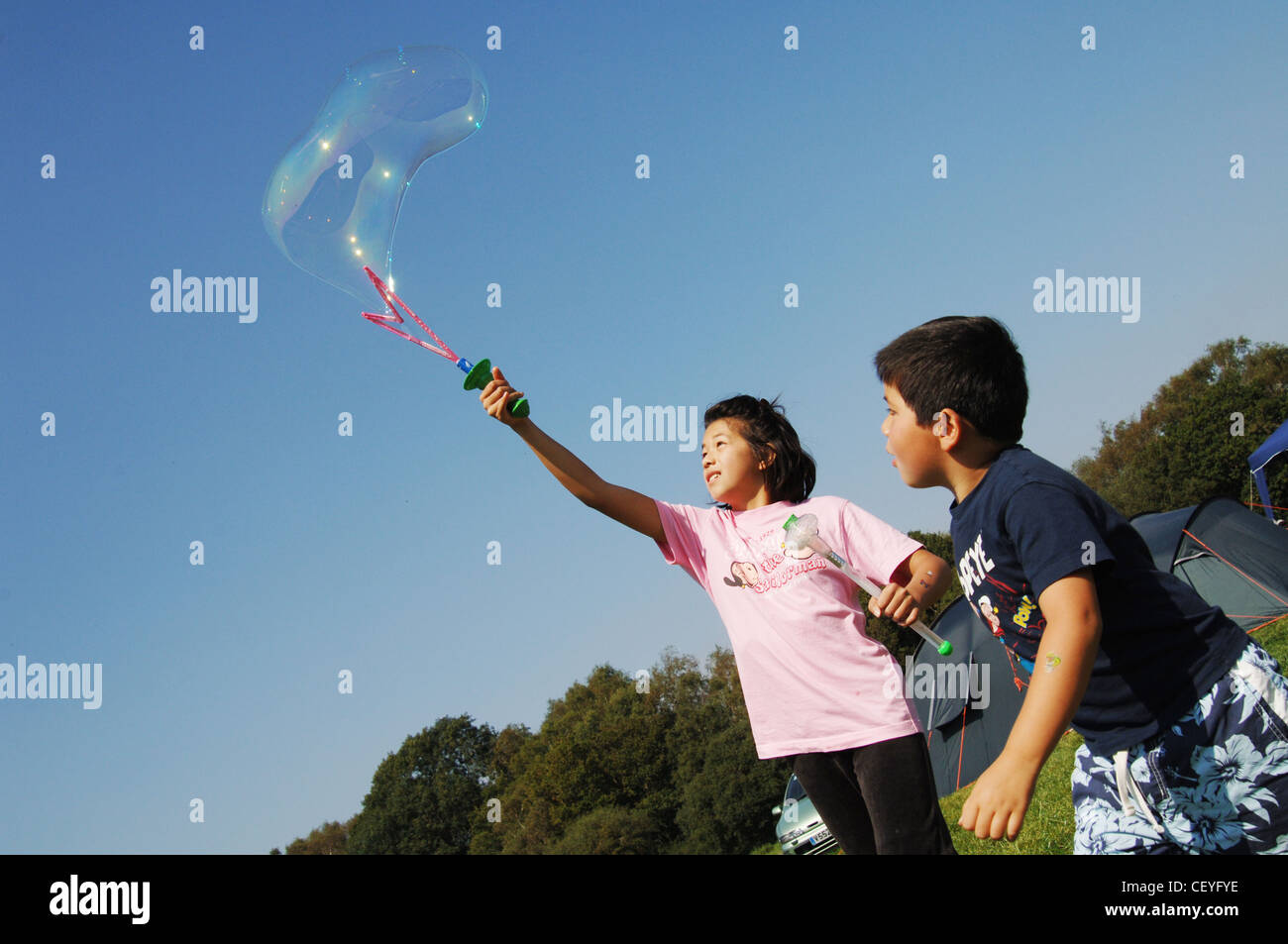 Fratello e Sorella rendendo bolle giganti con bolla di bacchetta magica al campeggio Kin Ho Foto Stock