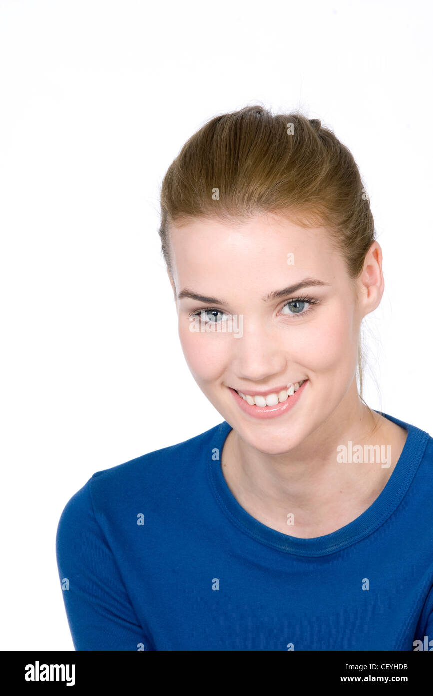 Femmina con capelli castani fuori la sua faccia, indossando una parte superiore blu, sorridente, guardando la fotocamera Foto Stock