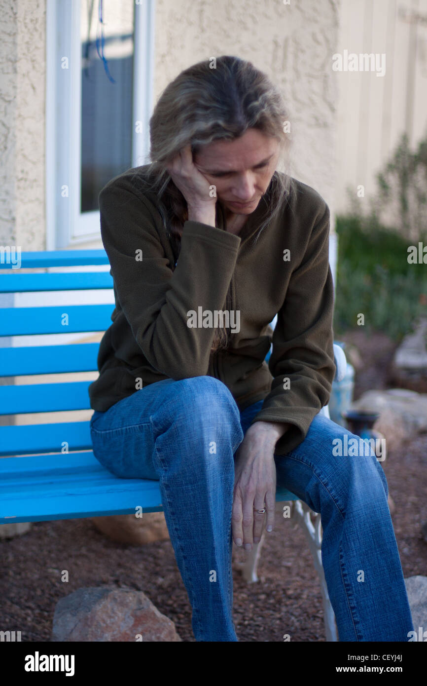 Donna seduta su un banco di lavoro premuto e frustrato Foto Stock
