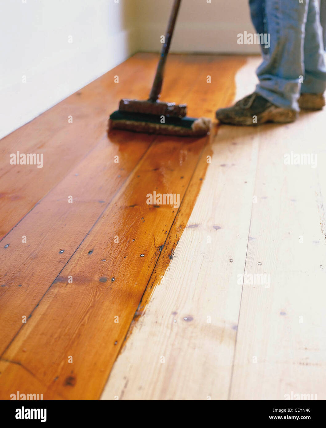 "Nuova" lifefloors prima: Anonimo maschio di spazzolatura legno sabbiato flowith flosealer vernice tramite lungo pennello gestite Foto Stock