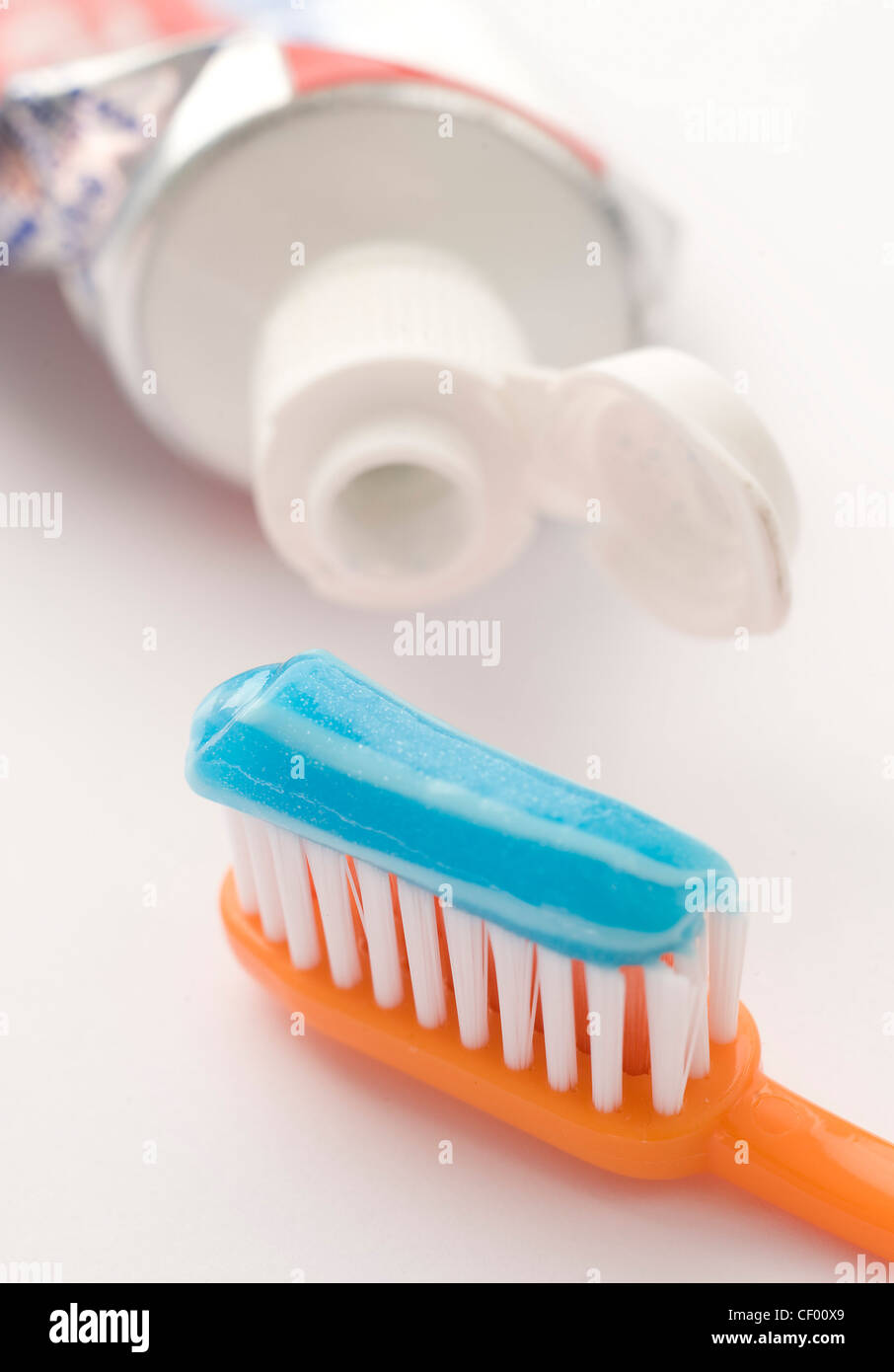 Un accartocciata tubo di dentifricio, di bianco e blu con pasta dentifricia  su un arancione spazzolino da denti Foto stock - Alamy
