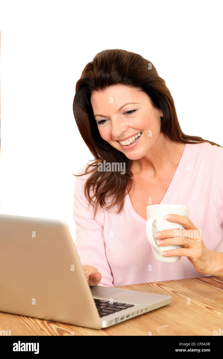 Donna felice con il suo computer portatile in cucina tenendo una tazza di tè o caffè, cut-out. Foto Stock