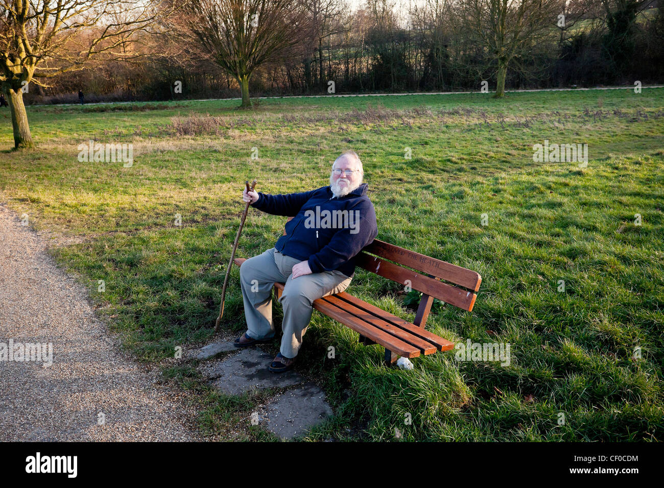 Un uomo anziano seduto su una panchina del parco, Londra, Inghilterra, Regno Unito. Foto Stock