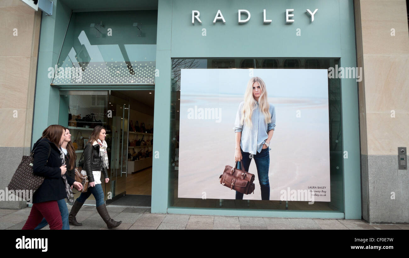 Giovani donne camminare davanti a un Radley borsetta, borsa e valigeria nella nuova area commerciale centro di Cardiff Wales UK Foto Stock