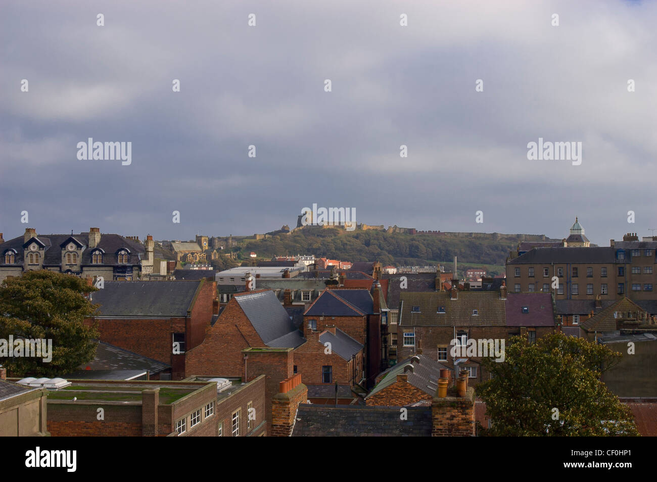 Città di Scarborough con il castello sul promontorio roccioso dietro in un giorno nuvoloso Foto Stock
