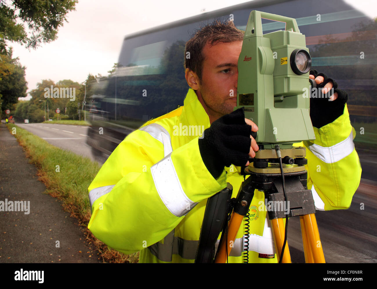 CWAC autorità locale surveyor su un556 bypass Northwich guardando in direzione di Chester con Leica strumento di indagine. Il passaggio di camion. Foto Stock