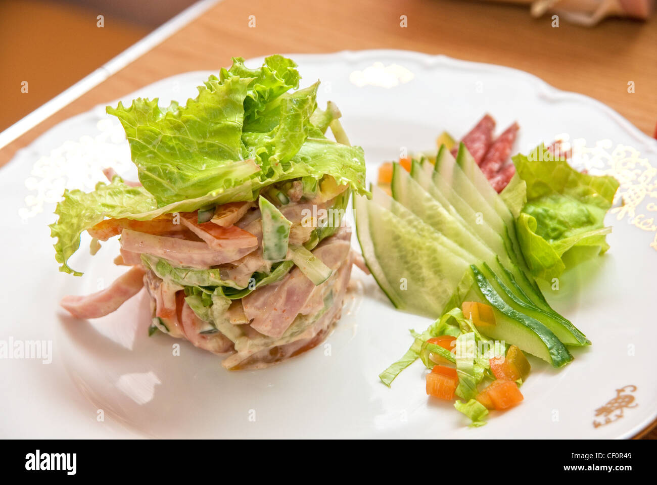 Insalata di diversi tipi di salsicce, cetrioli, peperoni, lattuga con panna acida salsa Foto Stock