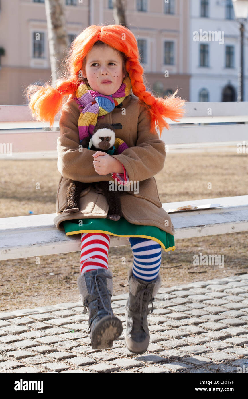 Bambina vestito come Pippi calza lunga seduta su una panchina nel