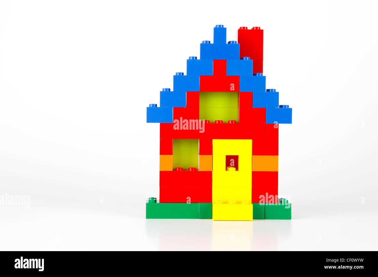 Una casa costruita di rosso, blu, giallo e verde tradizionali mattoni LEGO su uno sfondo bianco con lievi riflessi e ombre Foto Stock