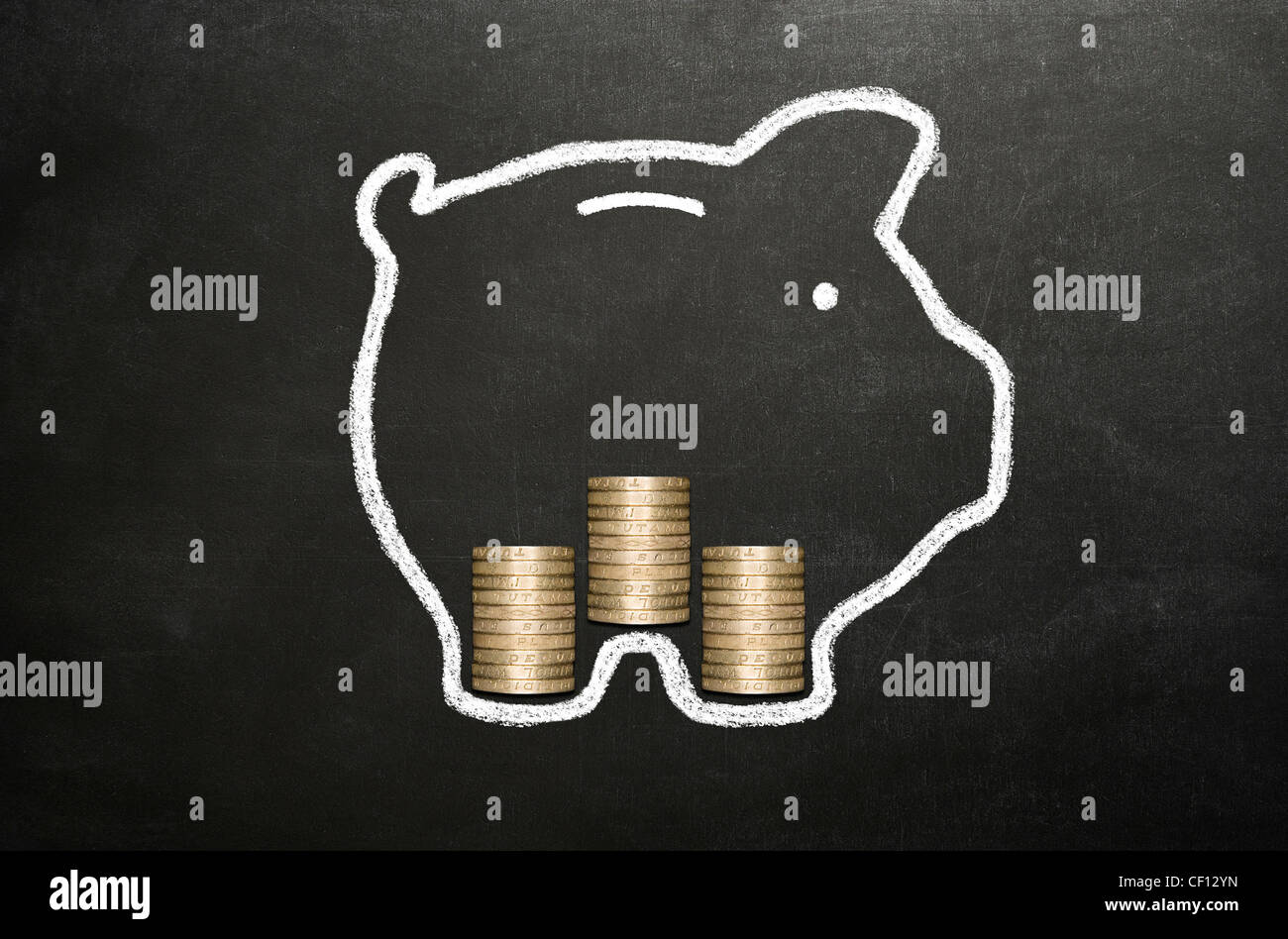 Salvadanaio disegnato in gesso su una lavagna con tre pile di real pound monete al suo interno. Foto Stock