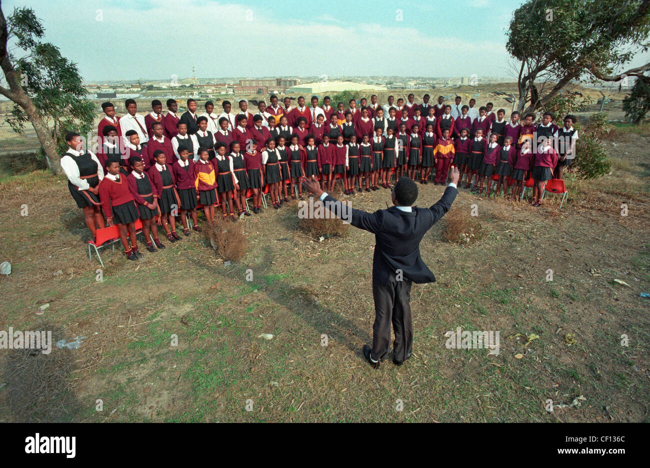 Il nero di scolari di cantare in un coro scolastico condotta dall'insegnante di musica in Port Elizabeth, Sud Africa. Foto Stock