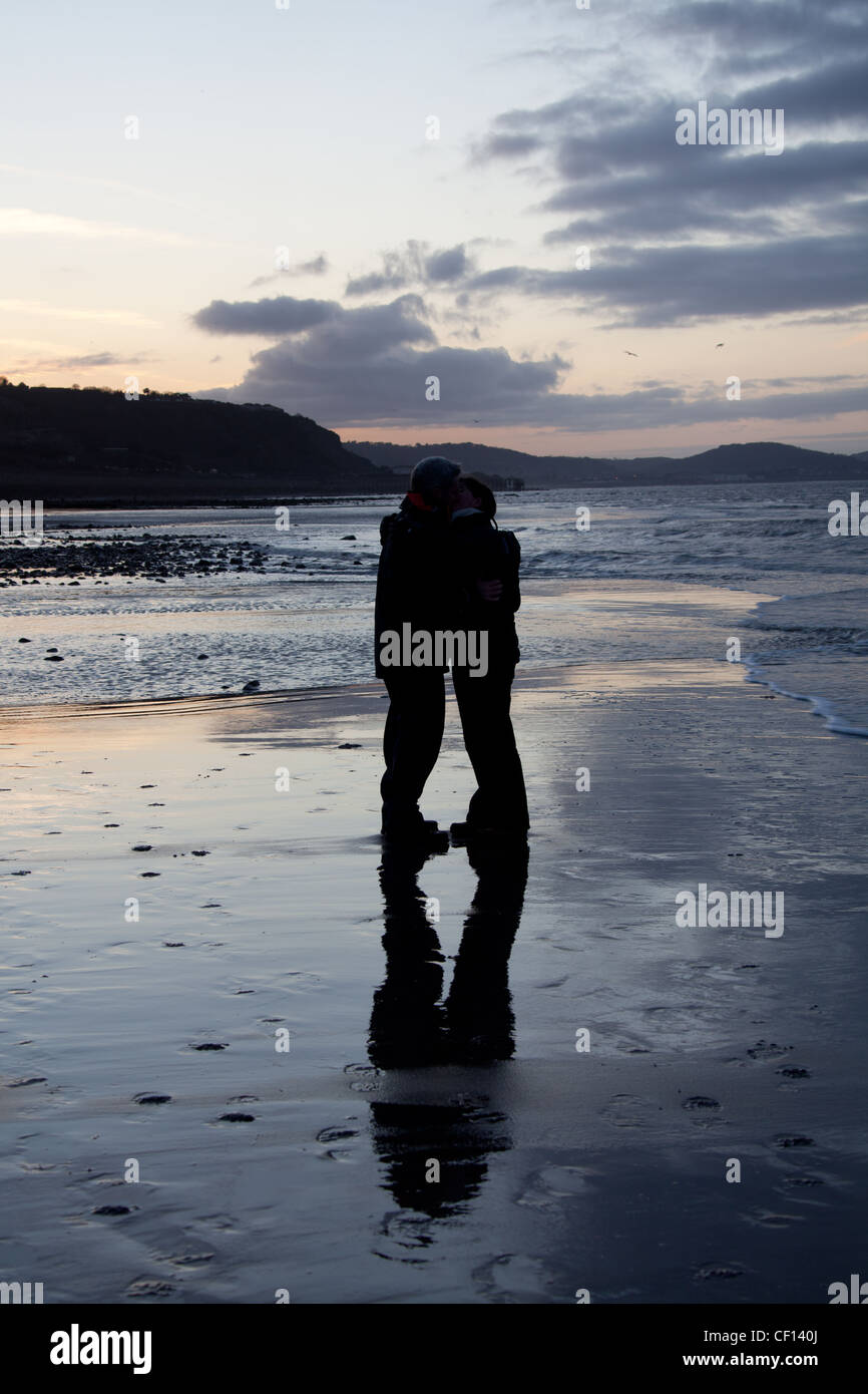 Giovane baciando su una costa del Galles settentrionale spiaggia con Colwyn Bay in background. Foto Stock