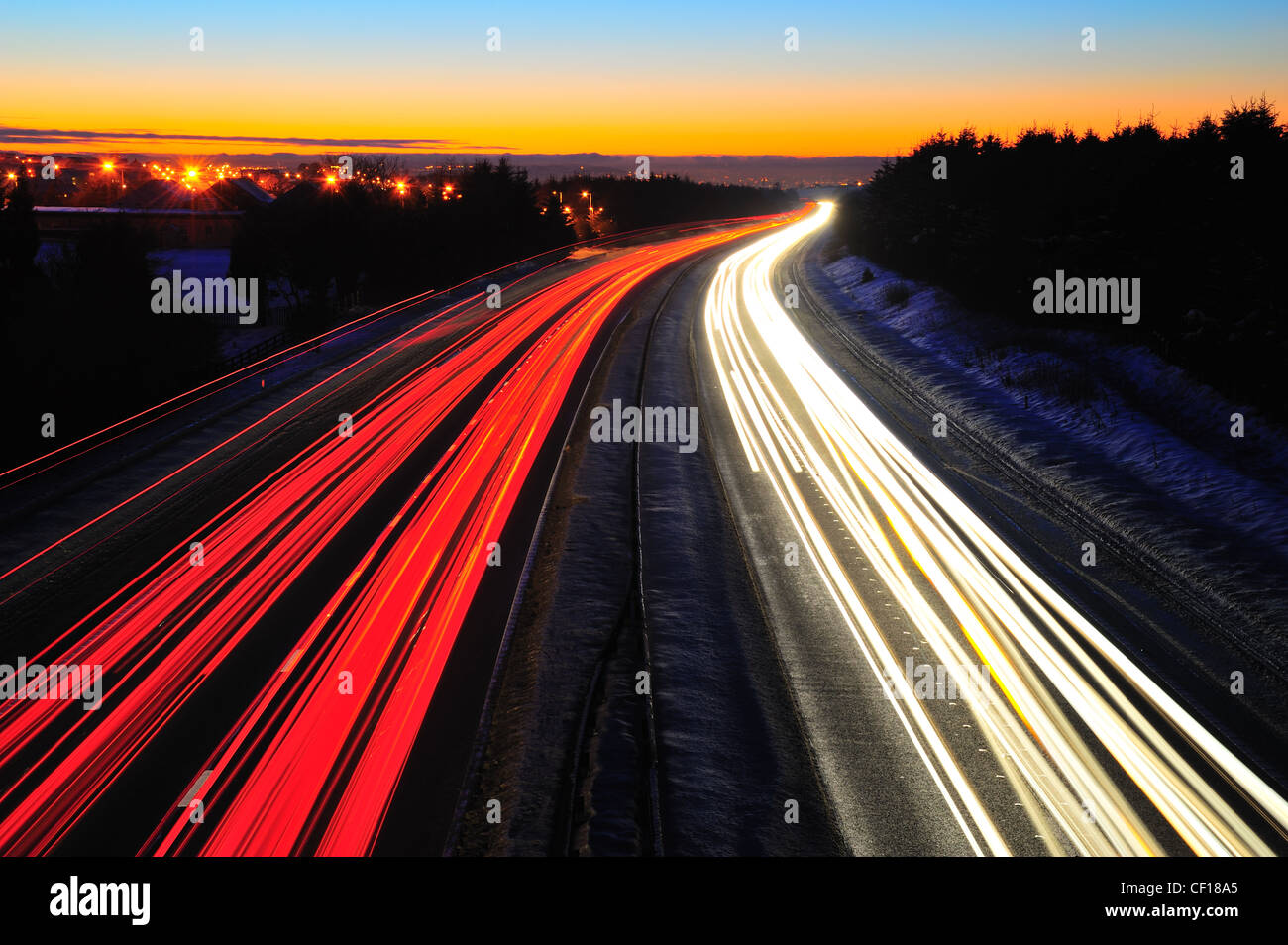 Traffico sentieri di luce sull'autostrada M8 in Scozia tra Glasgow e Edimburgo. Scattata di notte in inverno con neve sul terreno Foto Stock