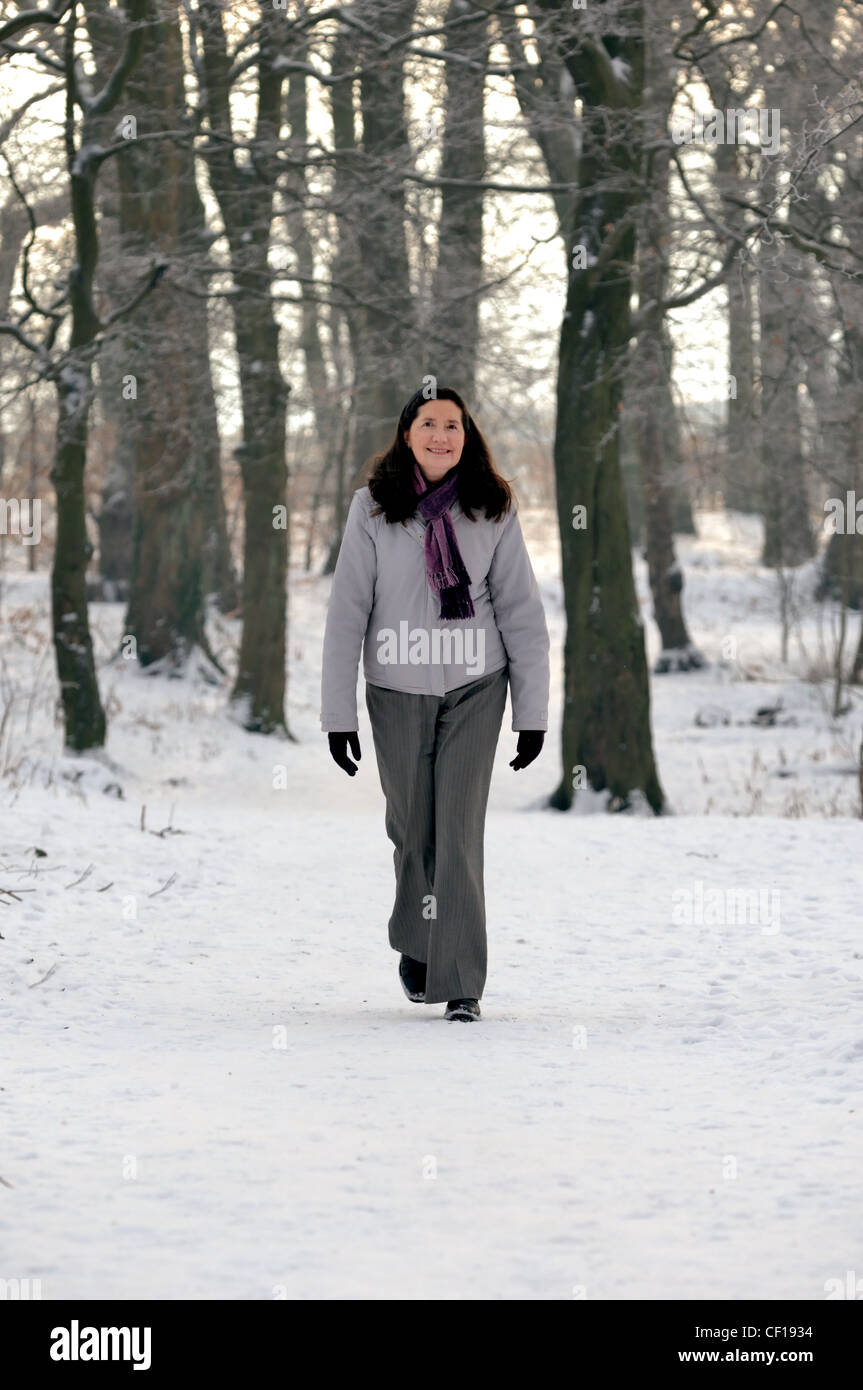 Donna di mezza età passeggiate nella neve Foto Stock