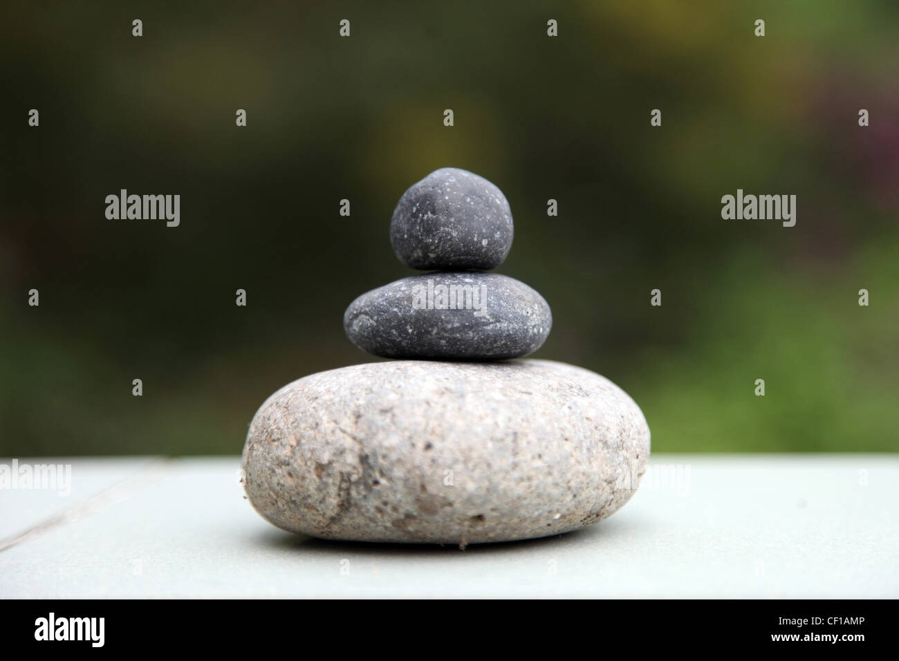 3 pietre sorge su ogni altri in equilibrio. Si tratta di un lettore Zen visual su una natura/sfondo verde. Si tratta di un simbolo di un benessere sano Foto Stock