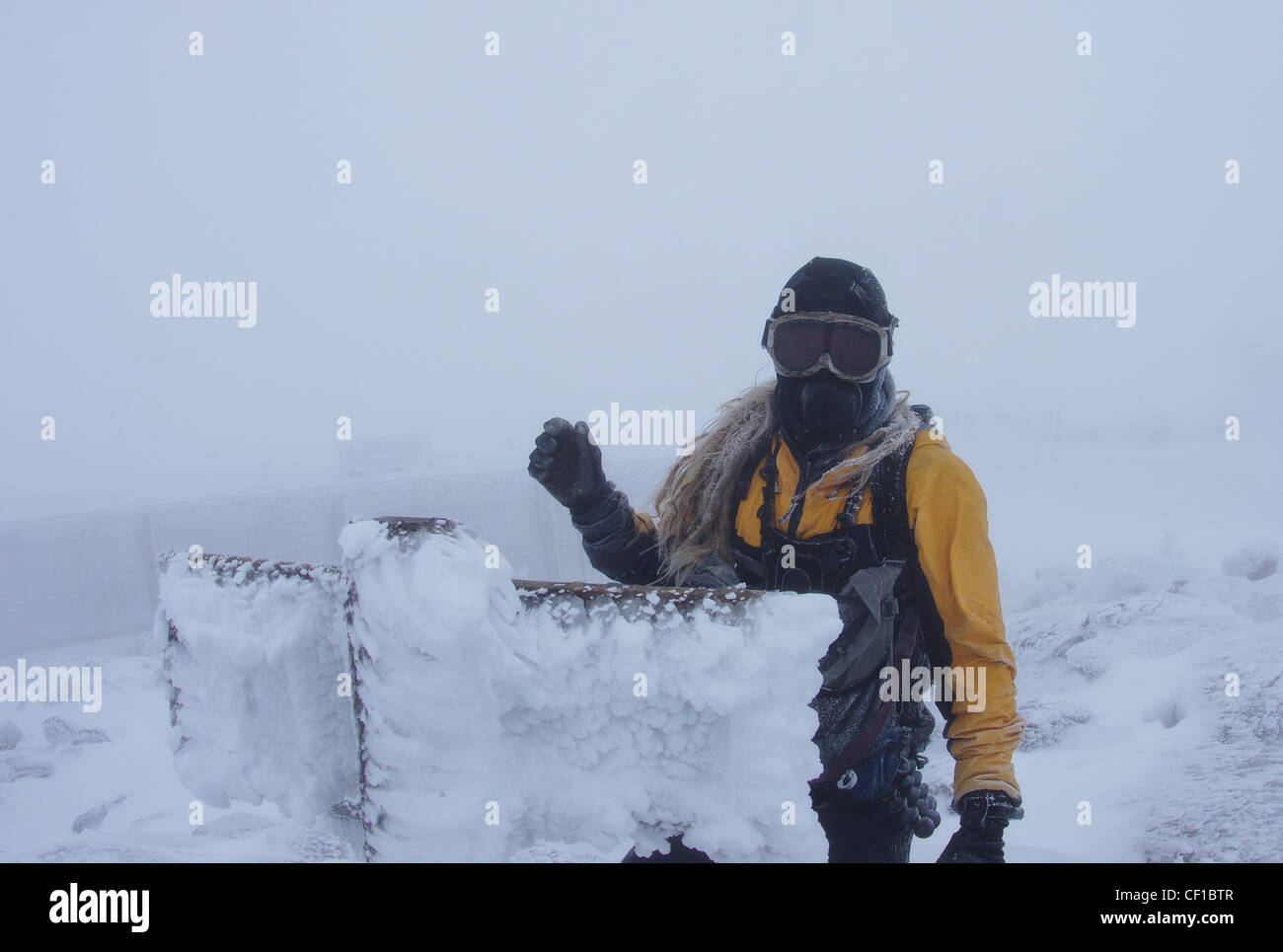 Un uomo sulla vetta del Monte Washington nel vicino whiteout condizioni con maschera viso e occhiali e rime ice Foto Stock