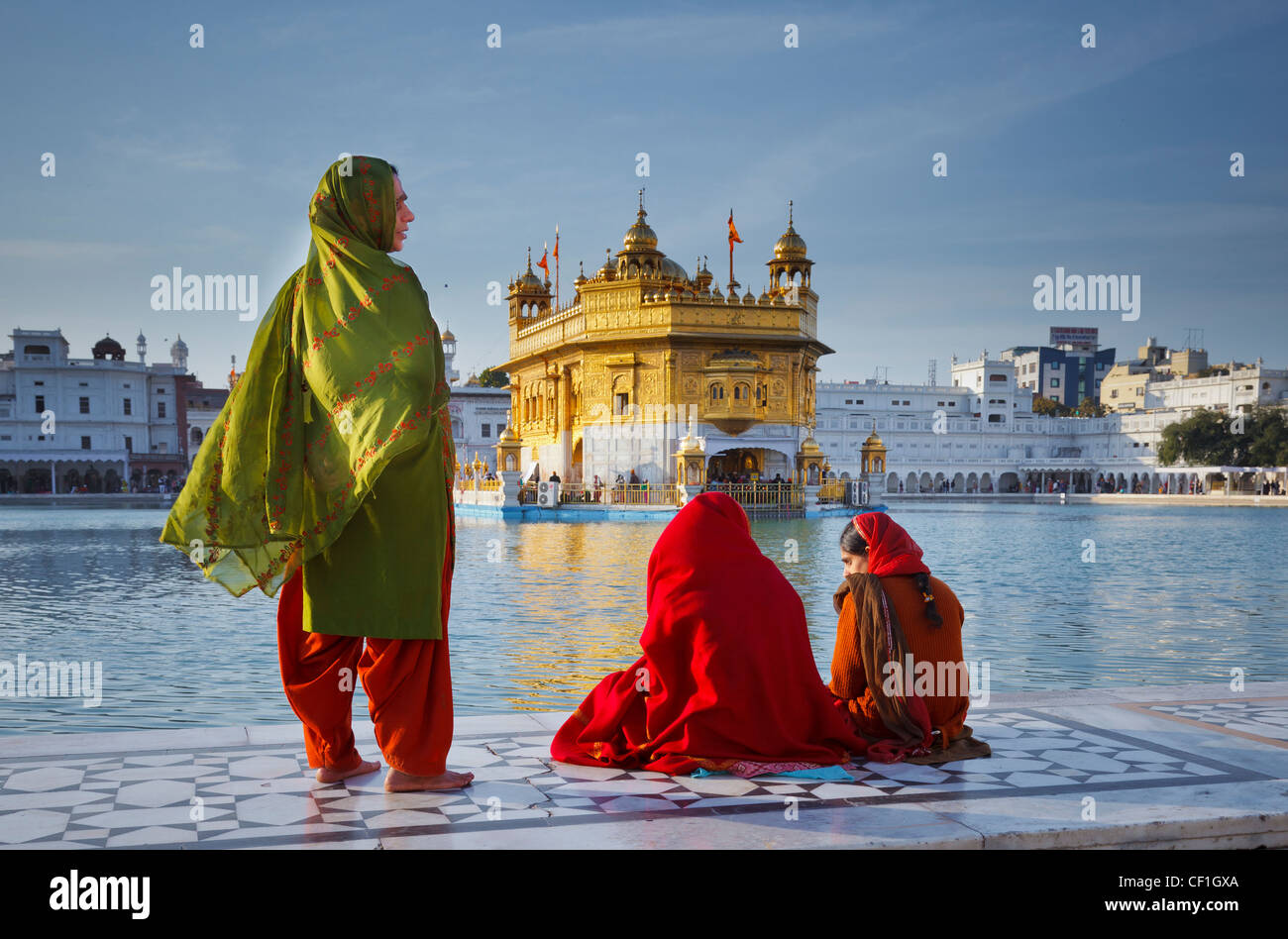 Tre donne indiane in rosso e verde di Sari davanti al tempio d'oro di Amritsar Punjab, India Foto Stock