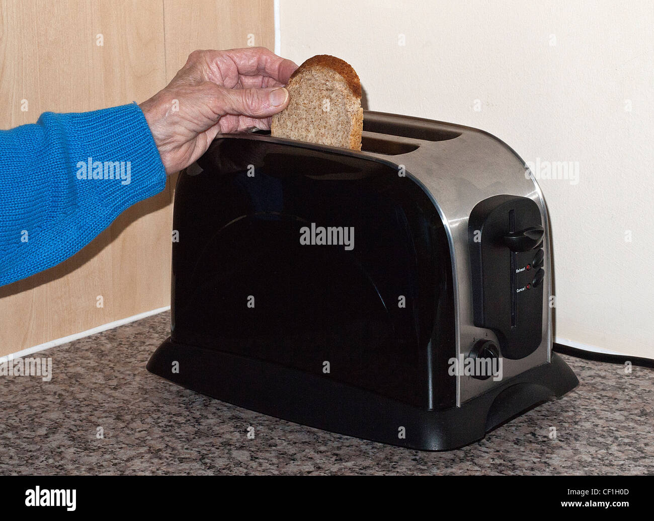 Signora mettendo una fetta di pane nel tostapane, Inghilterra, Regno Unito. Foto Stock