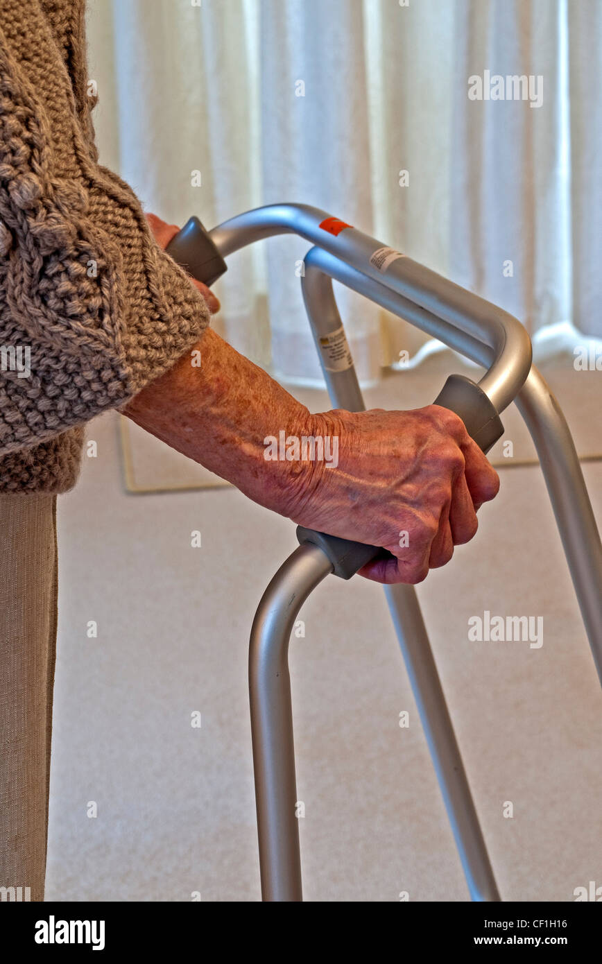 Signora anziana tenendo un Zimmer cornice o telaio a piedi per il supporto, Inghilterra, Regno Unito. Foto Stock