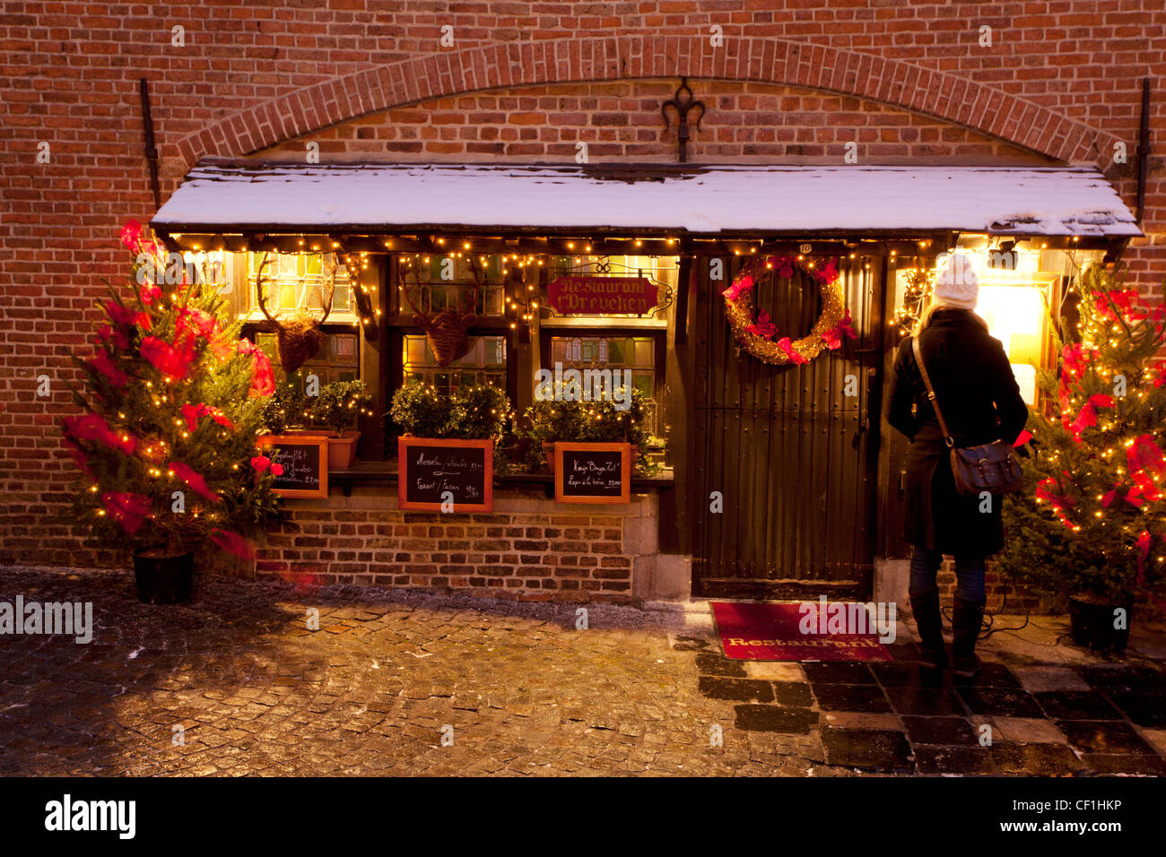 Una signora guarda il menu di Natale al di fuori di un ristorante in Bruges Foto Stock