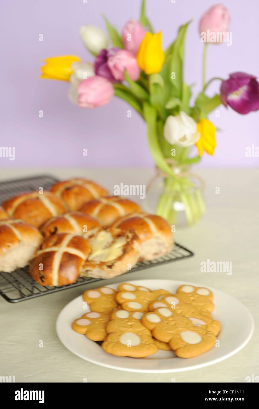 Una vita ancora immagine di un bouquet di tulipani colorati in vaso di vetro legata la corda, hot cross panini sulla rastrelliera metallica e bunny biscotti Foto Stock