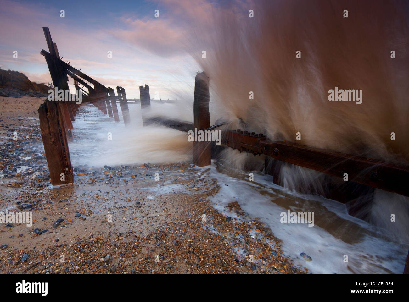 Una rottura dell'onda oltre le difese costiere a Happisburgh sulla costa di Norfolk. Foto Stock