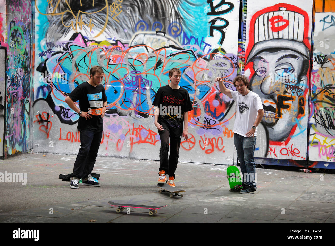 Skateboarders contro uno sfondo di graffiti sulla South Bank di Londra. Foto Stock