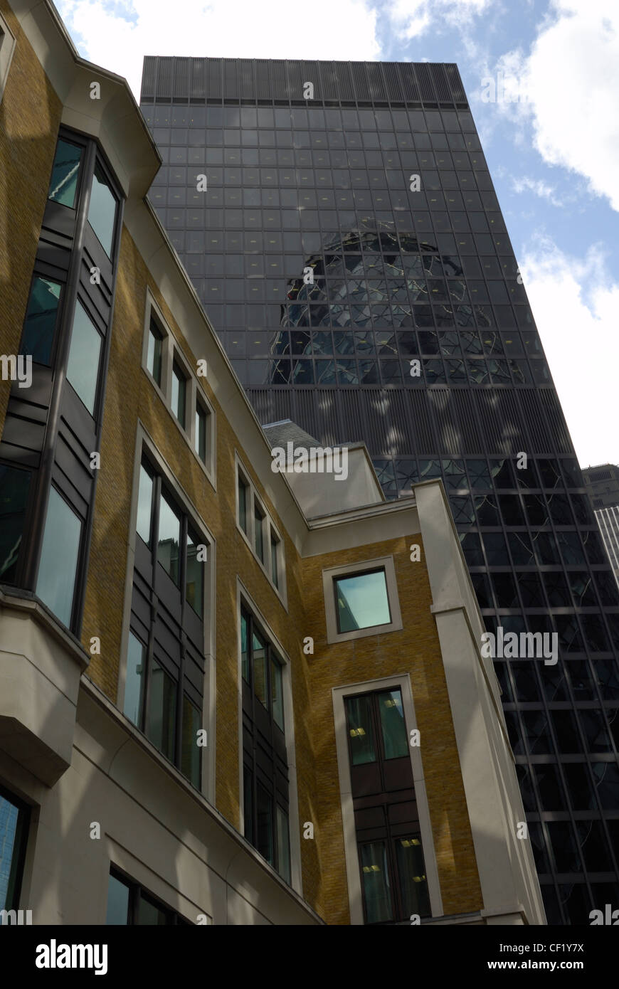 30 St Mary Axe, noto anche come il Gherkin riflessa nelle finestre di un blocco di uffici nella città di Londra. Foto Stock