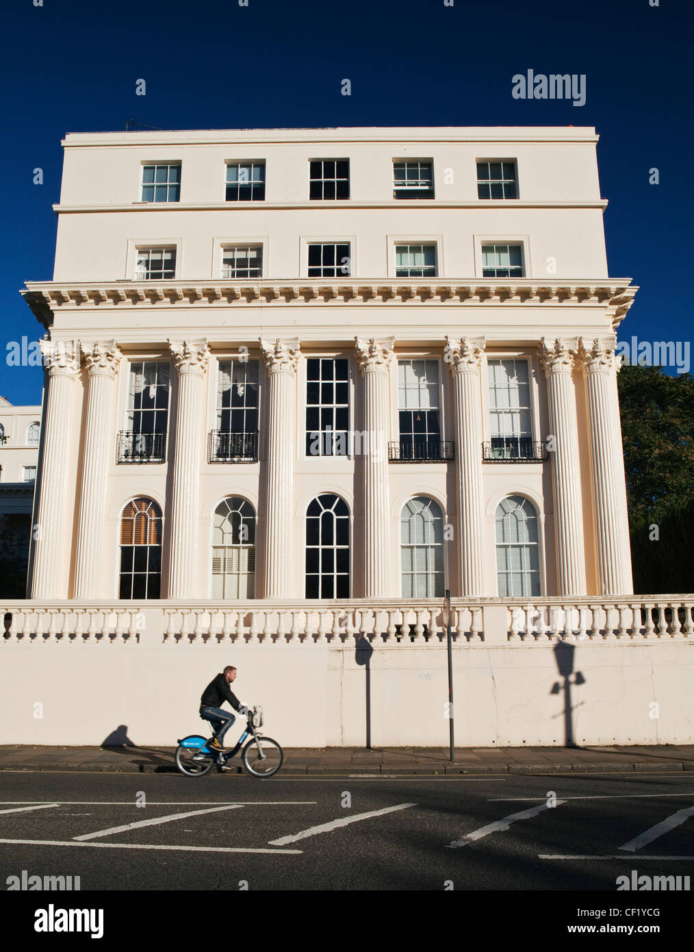 Un uomo in bicicletta utilizzando un "Boris moto' passato un XIX secolo stuccato edificio progettato dall architetto John Nash in Cumberland terrazza. Foto Stock