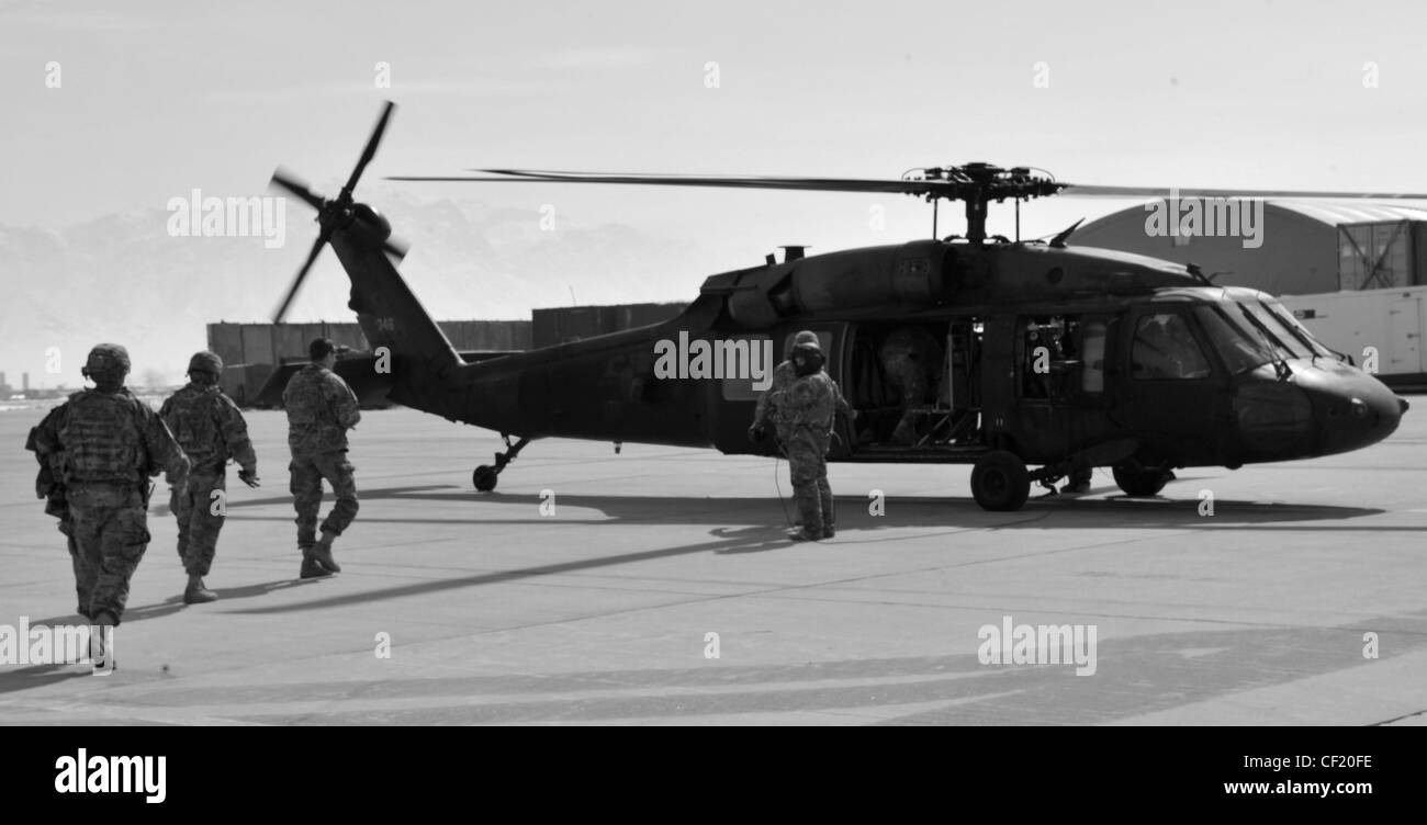 Un membro dell'equipaggio UH-60 Black Hawk assegnato A UNA Società, 3-82 Aviation Task Force Talon presso il campo aereo dell'Esercito di Bagram, dirige i membri del servizio durante il caricamento per un volo il 25 febbraio 2012. L'unità conduce missioni di circolazione sul campo di battaglia per la combinazione di Joint Task Force-1, Task Force Poseidon e Task Force Talon. Il Black Hawk UH-60 è in uso dalla fine degli anni '70 e continua ad essere uno degli elicotteri di trasporto tattico di™€ militaryâ più versatili e affidabili. Foto Stock